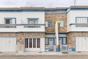 a building with blue and white doors and a street at 4 bedroom villa wi-fi and shared pool by ALGARVEMANTA in Manta Rota