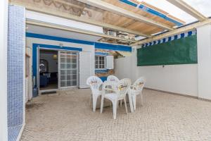 un patio con sillas blancas y una pizarra en 4 bedroom villa wi-fi and shared pool by ALGARVEMANTA, en Manta Rota