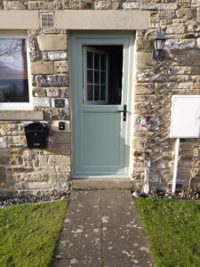 uma porta azul ao lado de uma casa de pedra em Demesnes View em Barnard Castle