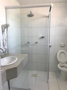a bathroom with a shower with a sink and a toilet at Farol Hotel in Torres