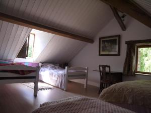 een slaapkamer op zolder met 2 bedden en een stoel bij La Grange in Saint-Père
