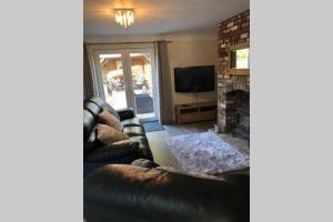 a living room with a leather couch and a fireplace at Dove Nest Cottage Blackpool Lytham St Annes in Lytham St Annes