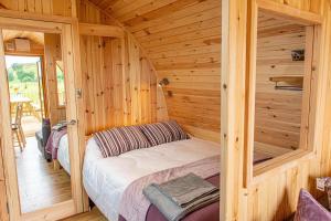 um quarto com uma cama num chalé de madeira em Farragon Luxury Glamping Pod with Hot Tub & Pet Friendly at Pitilie Pods em Aberfeldy