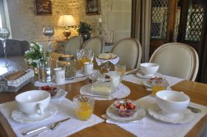 una mesa de comedor con platos, tazones y tazas en La Ferme Blanche, en Cussay