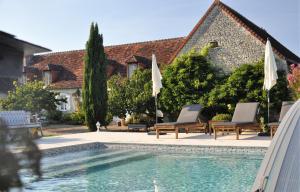 a pool in front of a house with two chairs and umbrellas at La Ferme Blanche in Cussay
