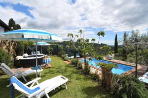 Un patio con sillas, una sombrilla y una piscina. en Francesca 3, en Camaiore