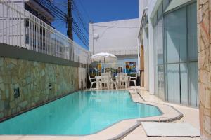 a swimming pool with a table and chairs next to a building at Rede Andrade Jangadeiro in Aracaju