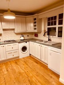 a kitchen with white cabinets and a washing machine at Waterside Star in Derry Londonderry