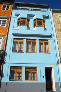ein blaues Gebäude mit orangefarbenen Fenstern auf einer Straße in der Unterkunft Apartments Porto Historico in Porto