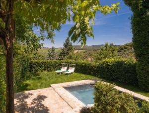 een tuin met 2 stoelen en een zwembad bij Canonica di Vertine in Gaiole in Chianti