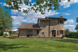 una antigua casa de piedra con césped verde en Poggio della Villa, en Radda in Chianti