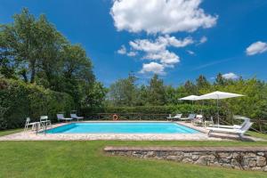 una piscina con sillas y sombrilla en Poggio della Villa, en Radda in Chianti