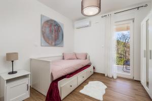 a white bedroom with a bed and a window at Villa Ines in Ičići