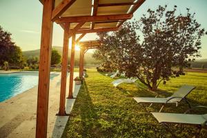 a wooden pergola with chairs next to a pool at Agriturismo Lunadoro in Monticchiello