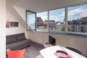 a living room with a couch and a table and windows at Le Fort Rouge, centre ville, quartier historique in Tournai