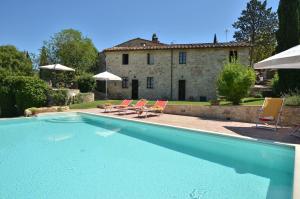 a swimming pool with two chairs and a house at La Rana in Gaiole in Chianti
