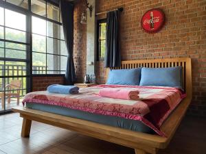 a bedroom with a bed with a brick wall at PilokMyhome ที่พักเหมืองปิล็อก บ้านอีต่อง in Ban Pilok Khi