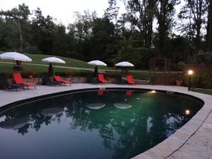 a swimming pool with chairs and umbrellas at Hostellerie Restaurant Les Gorges de l'Aveyron in Bruniquel