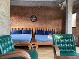 two beds in a room with chairs and a brick wall at PilokMyhome ที่พักเหมืองปิล็อก บ้านอีต่อง in Ban Pilok Khi
