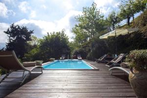 una piscina con sillas y una terraza de madera en Villa Giovannino, en Camaiore