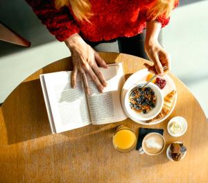 a woman reading a book on a table with a bowl of food at citizenM Tower of London in London