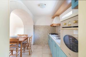 莫諾波利的住宿－Trullo Amare，厨房配有蓝色橱柜和桌椅