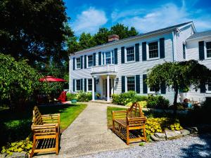 two wooden chairs in front of a white house at The Homestead in Madison