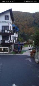 a large white house with a woman sitting on a bench at HOTEL ALL TIMES in Timisul de Jos