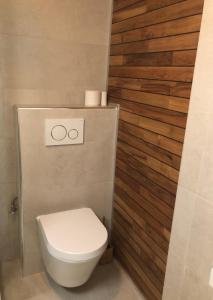 een badkamer met een toilet en een houten muur bij Appartement sur la digue in Knokke-Heist