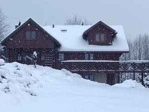 a house covered in snow with a pile of snow at Kocisówka in Lipowa