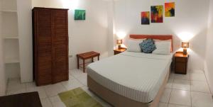 a bedroom with a bed and two lamps on two tables at Tropical Apartments Tobago in Scarborough