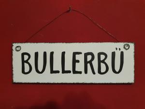 a white sign with the word bullpen hanging on a red wall at Ferienhof Schild - Das kleine Bullerbü am Meer in Wangerland +36 photos
