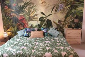 a bedroom with a bed with a tropical wallpaper at Studio Jungle in Saint-Épain