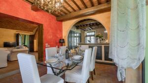 Un comedor con una mesa de cristal y sillas blancas. en Poggio alle Fonti 11, en Montevarchi