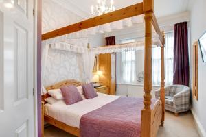 ein Schlafzimmer mit einem Himmelbett in einem Zimmer in der Unterkunft Trelawney Hotel - Guest House in Torquay
