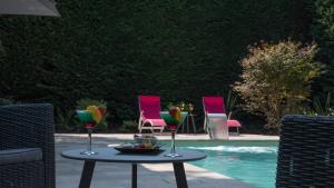 a table with wine glasses and chairs next to a pool at Logis Hotel La Croix Blanche Fontevraud in Fontevraud-l'Abbaye
