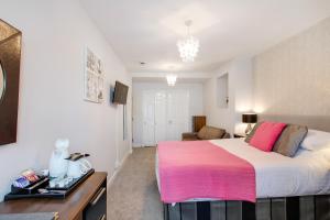 a bedroom with a large bed with a pink blanket at Trelawney Hotel - Guest House in Torquay