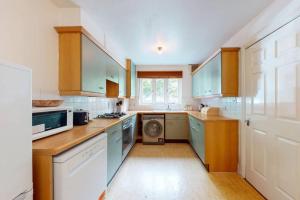 a kitchen with blue cabinets and a washing machine at Super 2 bed House wPrivateParking&PrivateGarden in London