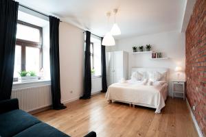 a bedroom with a white bed and a brick wall at Apartamenty Dukla in Dukla