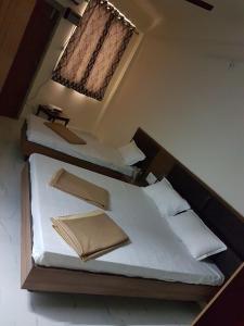 2 camas en una habitación con sábanas y almohadas blancas en K K RENUKA DHARAMSHALA, en Haridwar