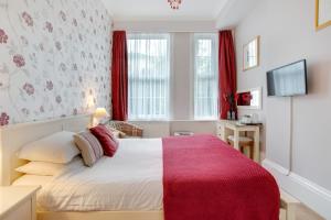 um quarto com uma cama grande e um cobertor vermelho em Trelawney Hotel - Guest House em Torquay