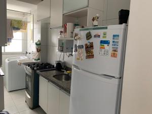 a kitchen with a white refrigerator and a sink at Apartamento Aruana a 3 Km da praia in Atalaia Velha