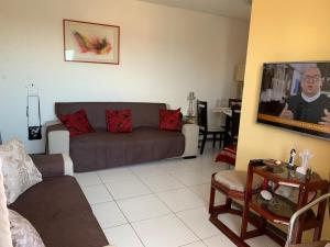 a living room with a couch and a flat screen tv at Apartamento Aruana a 3 Km da praia in Atalaia Velha