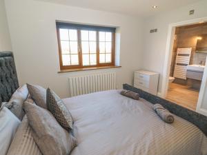 a bedroom with a bed with pillows and a window at Afon Rhos Bach in Caernarfon