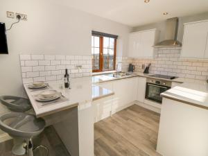 a white kitchen with a sink and a toilet at Afon Rhos Bach in Caernarfon