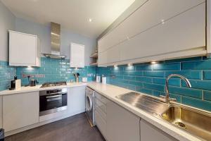una cucina con armadi bianchi e piastrelle blu di Modern 2 Bed Flat - The Black Dog Pub APT - 6 mins from Vauxhall station a Londra