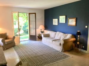 a living room with a white couch and a blue wall at Dans la bastide de Domme - piscine chauffée, parking privé in Domme