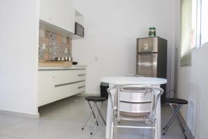 uma cozinha com uma mesa, 2 bancos e um frigorífico em Solar Água Pipa #260 - Apê na Praia por Carpediem em Pipa