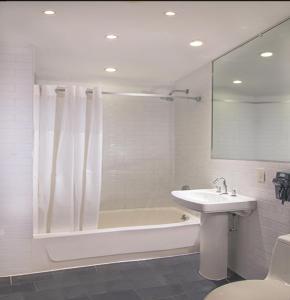 a bathroom with a sink and a bath tub and a mirror at Night Hotel Broadway in New York