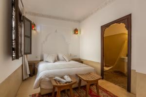 a bedroom with a bed and two chairs and a mirror at Riad Amin in Marrakesh